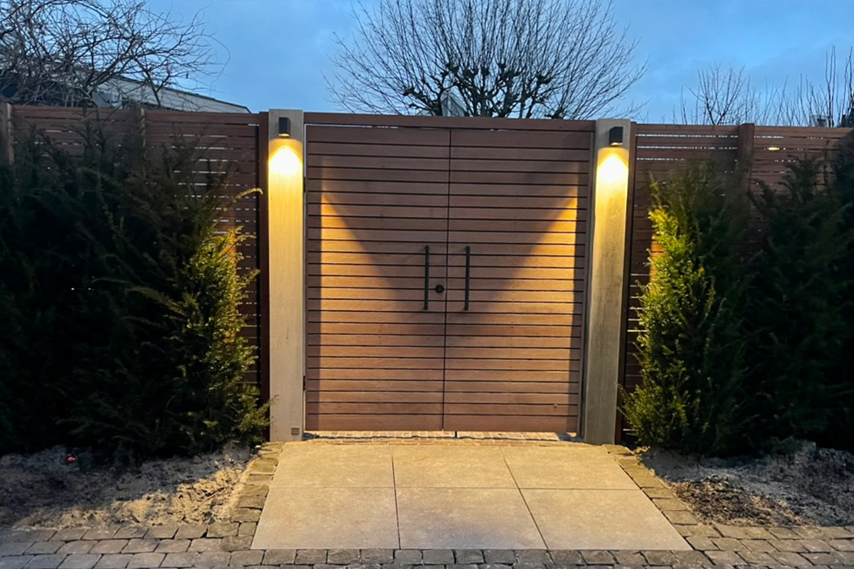 Custom gate and fence project featuring modern horizontal wooden slats, integrated ground lighting, and contemporary design