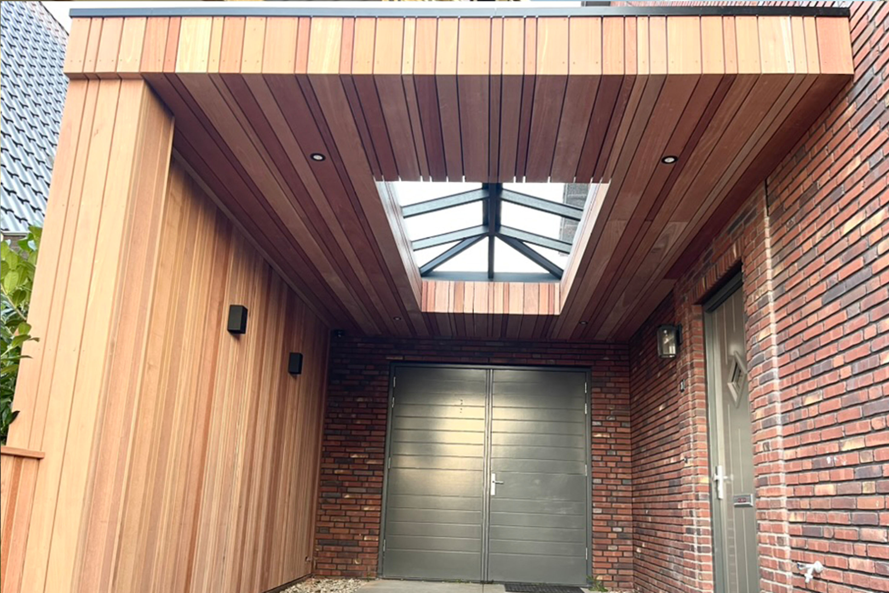 Modern wooden overhang with glass ceiling panels and brick walls in custom outdoor living space